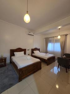 a bedroom with two beds and a chair and a table at Paramount Boutique Hotel in Entebbe
