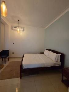 a bedroom with a bed and a chair at Paramount Boutique Hotel in Entebbe +4 photos