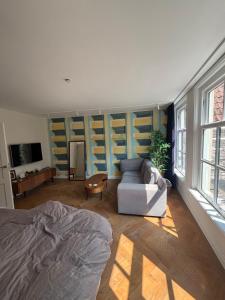 a room with a bed and a couch and windows at Zwols stadshuis in Zwolle