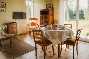 a dining room with a table with chairs and a television at Gîte Les Fresnes in Sainte-Honorine-des-Pertes