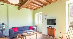 a living room with a blue couch and a tv at Gîte Les Fresnes in Sainte-Honorine-des-Pertes