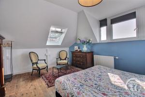 a bedroom with a bed and two chairs and a dresser at Kermaria la maison d'hôtes in Plougrescant