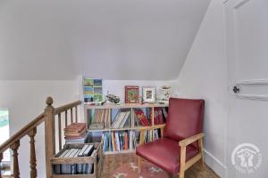 a red chair sitting next to a book shelf with books at Kermaria la maison d'hôtes in Plougrescant