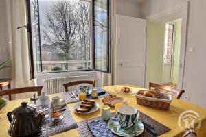 a table with food and a basket of bread on it at Kermaria la maison d'hôtes in Plougrescant