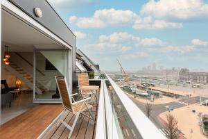 a balcony with a chair and a view of a city at Whaaw Oostende in Ostend