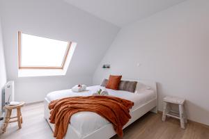 a white bedroom with a bed with an orange blanket on it at Whaaw Oostende in Ostend