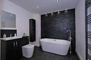a bathroom with a white tub and a black brick wall at Kirkton House in Kirkton of Skene