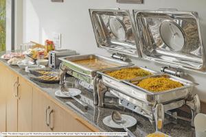 a kitchen counter with several trays of food at Treebo Golden Palm, Civil Lines in Jabalpur