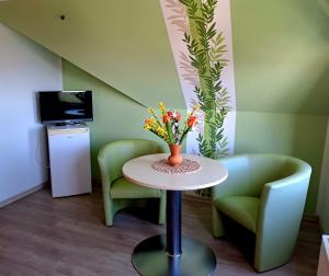 a room with two chairs and a table with flowers on it at Schullandheim Sohland Spree in Auf der Wiese