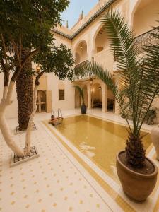 a courtyard with a pool in a building with trees at Riad Maison Palmier in Marrakesh