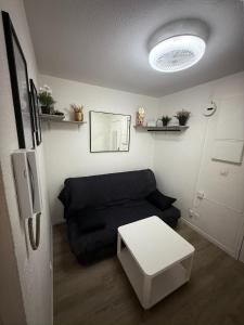 a living room with a black couch and a white table at Paisible studio fonctionnel in Cluses