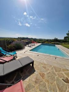 a large swimming pool with chairs and a table at Fonbanoux in Flavignac