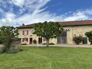 a large stone house with a tree in the yard at Fonbanoux in Flavignac