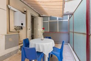 a table in a room with blue chairs and a vase of flowers at Appartamento Rina Centro Sicilia in Pietraperzia +18 photos
