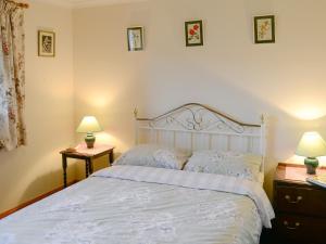a bedroom with a white bed with two night stands and two lamps at Lower Brae in Achnahanat +10 photos