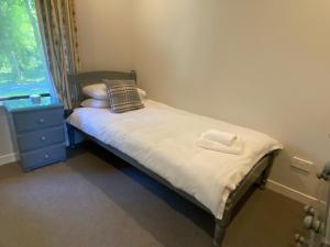 a small bedroom with a bed and a window at Puffin - Bach in Lerags