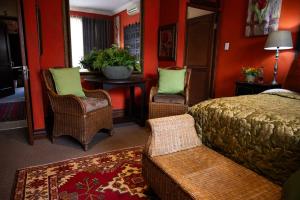 a bedroom with a bed and two chairs and a table at Tuscan Rose in Bloemfontein