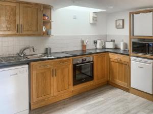 a kitchen with wooden cabinets and a sink at Lee Cottage - E4343A in Holy Island