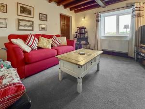 a living room with a red couch and a coffee table at Broadmeadows Farm in Butterton