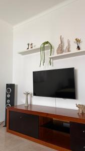 a flat screen tv sitting on top of a wooden entertainment center at Casa da Margarida in Castro Marim
