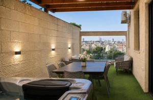 a patio with a table and chairs with a view at GABRIEL APARTMENTS - Jacuzzi & Panoramic JLM View Steps to Shaare Zedek Hospital in Bayit Wegan