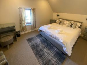 a bedroom with a large white bed with a desk at Puffin - Dubh Segir in Lerags