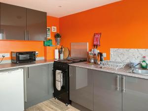 a kitchen with orange walls and a stove top oven at Orange Yurt - Uk48018 in Gamrie