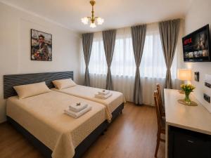 ein Schlafzimmer mit Bett, Schreibtisch und Vorhängen in der Unterkunft Hotel M in Nürnberg
