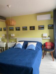 a bedroom with a blue bed and a chair at La Maison Angèle in Caisnes