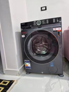 a washing machine sitting in a corner of a room at Thebes Guest house in Jazīrat al ‘Awwāmīyah