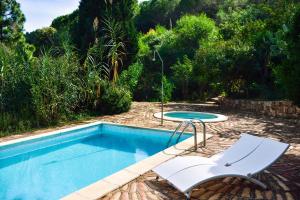 a swimming pool with a chair and a table at Finca Fiori 1 in Is Molas 