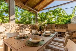 a wooden table with chairs and a bottle of wine at Villa Loznati in Cres