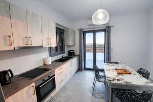 a kitchen with a table and a dining room with a window at Villa Therme Athen - Sea View Jacuzzi Santorini Stay in Emporio