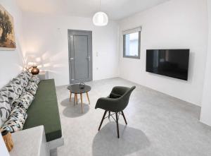 a living room with a couch and a chair and a television at Villa Therme Athen - Sea View Jacuzzi Santorini Stay in Emporio