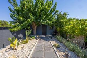 a garden with a tree and a walkway at Kálos Housing - Adults Only in Kolymbia