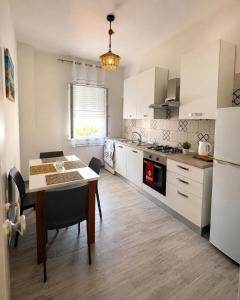 a kitchen with white cabinets and a table with chairs at La Finestra Sul Mare in Torretta