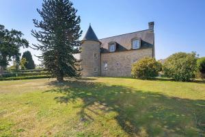 a large brick building with a tree in a field at La tourelle de la croix in Picauville