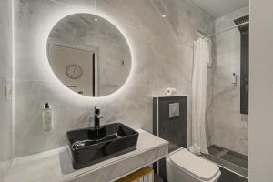 a bathroom with a sink and a mirror and a toilet at Doliva Studio 6 with private pool in Agios Gordios +27 photos