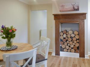 a table with a vase of flowers and a fireplace at Lantern Cottage in Lyndhurst