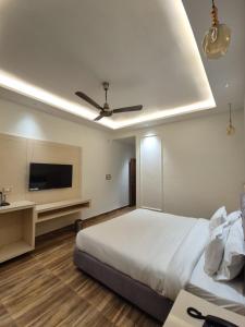 a bedroom with a bed and a flat screen tv at Hotel Satyaki Orchid in Katra