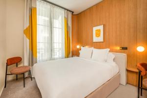a hotel room with a large white bed and a window at Maison Honnel in Paris