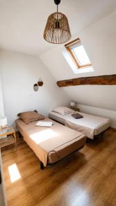 two beds in a attic room with a window at Gîte du Noyer in Villexanton