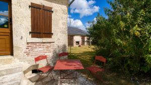 two red chairs and a table in a yard at Gîte du Noyer in Villexanton