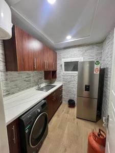 a kitchen with a stainless steel refrigerator and wooden cabinets at Tchaopremium in Lomé