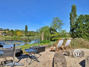 a group of chairs and a table and a lake at La Roche des Eaux Vives, 2 personnes in Fromentières
