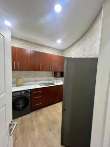 a kitchen with a stainless steel refrigerator and wooden cabinets at Tchaopremium in Lomé +6 photos