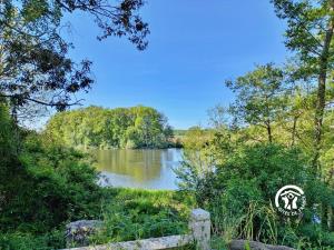 a view of a river with trees in the background at La Roche des Eaux Vives, 2 personnes in Fromentières