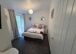 a small bedroom with a bed with two dolls on it at Meadows End Lodges in Cartmel