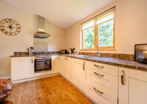 a kitchen with white cabinets and a sink and a window at Meadows End Lodges in Cartmel