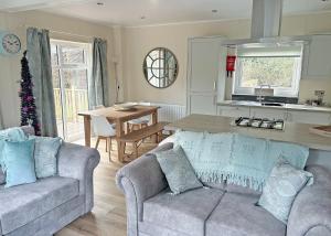 a living room with two couches and a kitchen with a table at Meadows End Lodges in Cartmel +245 photos